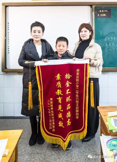 失主为感谢拾金不昧好少年王启骅同学,特地到金乡县实验小学颁发锦旗