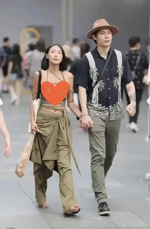 四川成都,一位光脚的女子和一位成熟稳重的男子手牵手走过热闹的